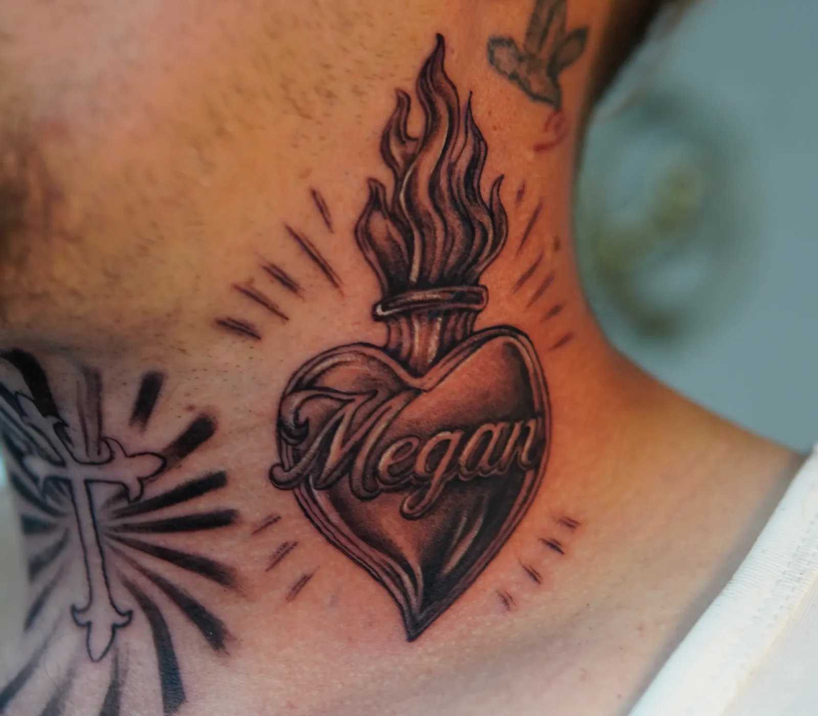 Black-and-grey sacred heart and flame tattoo on the side of the neck