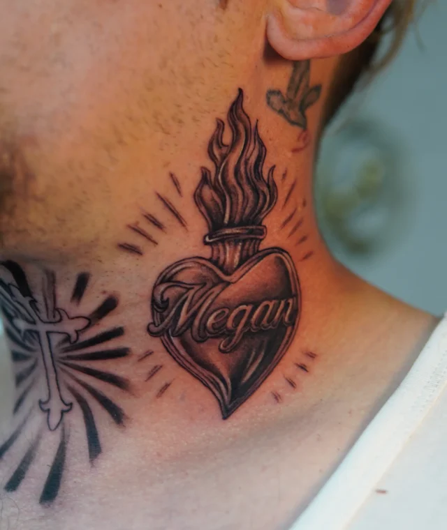 Black-and-grey sacred heart and flame tattoo on the side of the neck
