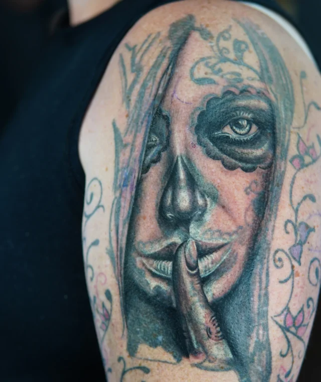 Black-and-grey mystical woman cover-up tattoo with roses on the upper arm